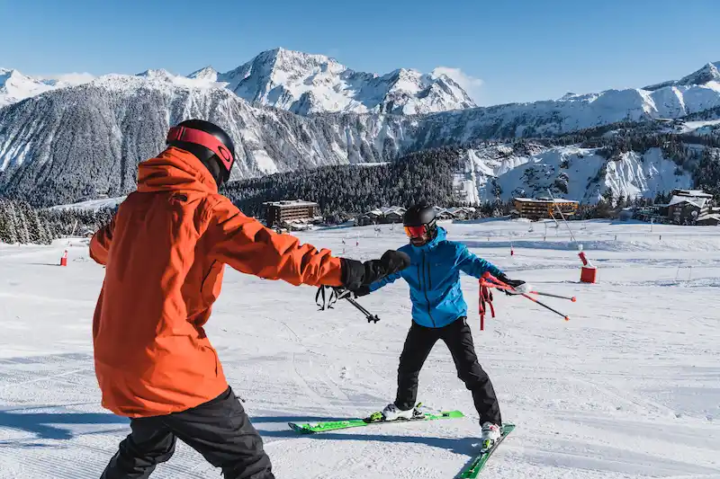 A Maison Sport instructor and a learner sharing a fist bump on the piste at Courchevel